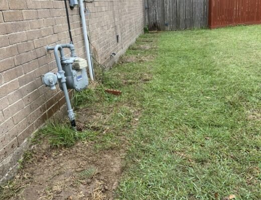 Electric meters relocated along a brick fence as part of Bonilla Foundation Repair's job site preparation in Houston