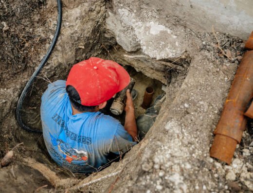 Hercules Foundation Repair crew member excavating an access pit around a pipe for foundation repair work in Houston
