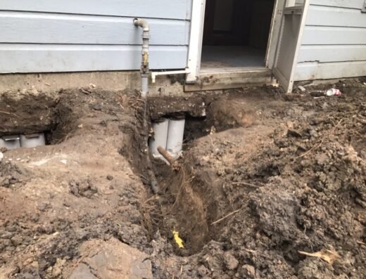 J R Foundation Repair crew digging a drainage trench with pipe along a home's foundation in South Houston