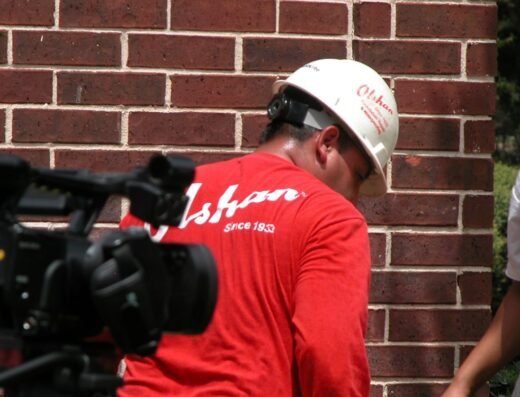 Uniformed Olshan Foundation Repair technician inspecting a brick wall foundation in Houston
