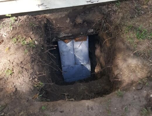 Excavated access pit next to a Houston home's siding exposing a concrete foundation pier, from PR Foundation Repair's own project photos