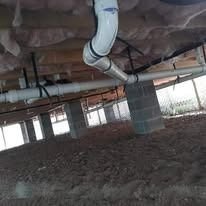 Crawl space beneath a Houston home showing PVC plumbing and concrete block support piers after Tomas Foundation Repair's work