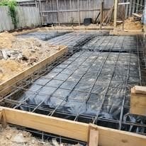 Concrete slab foundation under construction with a rebar grid over a moisture barrier, a recent Tomas Foundation Repair project in Houston
